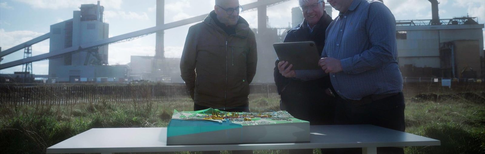 Three people viewing a 3D AR map of Teesside on an iPad outdoors